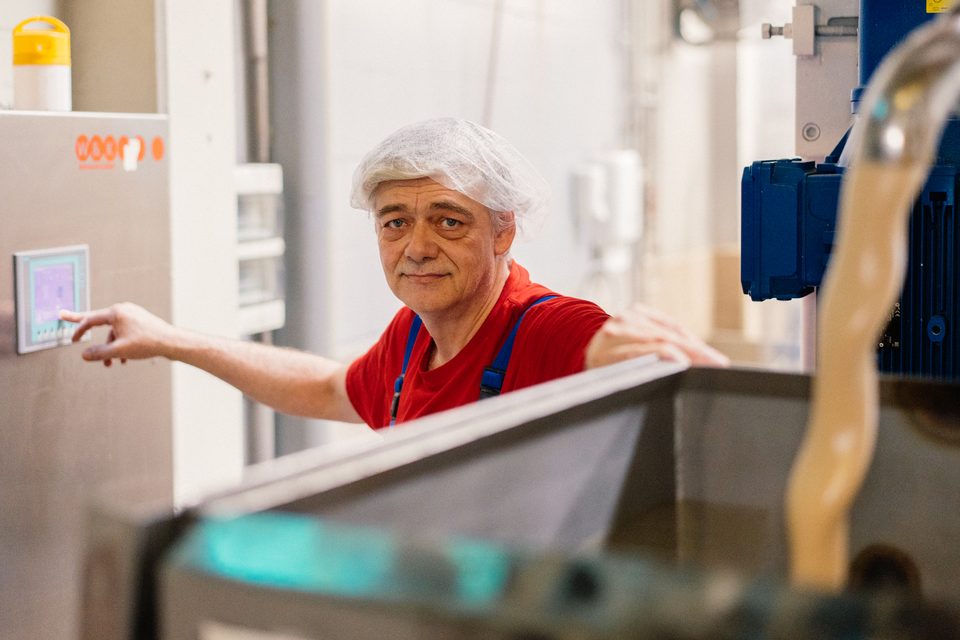 Mitarbeiter im roten Oberteil bedient das Steuerpanel einer Waffelanlage